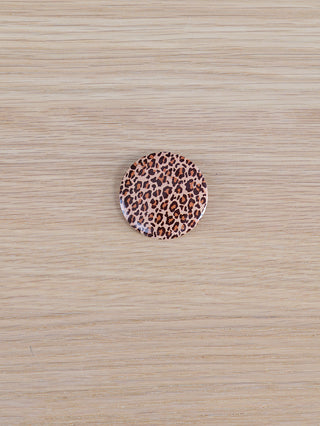 OFF#DLY Sticker Leo: Rundes Ansteckpatch mit Leopardenmuster auf Holzoberfläche, aus Kunststoff/Metall.