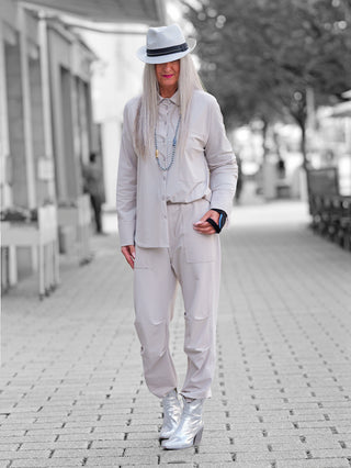 Eine Person trägt die Penn & Ink Bluse sand, eine oversized, beige Bluse mit markanter Brusttasche, weiten Ärmeln und breiten Manschetten, kombiniert mit passenden lockeren Hosen.