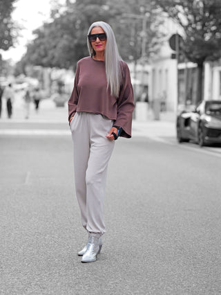 Penn&Ink Trousers T 1182 sand, locker geschnittene Jogpant mit elastischem Bund, sportiven Rippdetails und seitlichen Eingrifftaschen, getragen von einer Frau in einer lässigen Streetstyle-Szene.