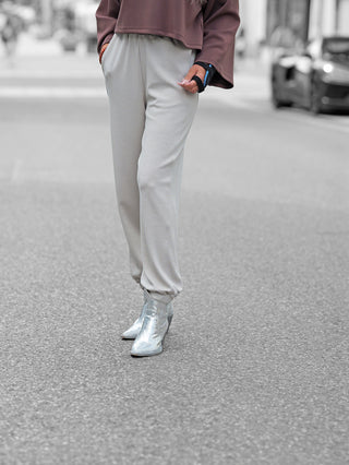 Penn&Ink Trousers T 1182 sand präsentiert sich als lässige Jogpant in Hellgrau, getragen mit silbernen Boots. Elastischer Bund und seitliche Taschen unterstreichen den bequemen Streetstyle-Look.