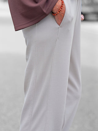 Nahaufnahme der Penn&Ink Trousers T 1182 sand: Lichtgraue Jogpant mit elastischem Bund und seitlichen Taschen, getragen mit Hand in der Tasche. Mauvefarbenes Oberteil und rotes Armband ergänzen den Look.