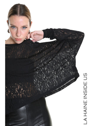 La Haine Sweater black LW5205: Frau in lockerem, semitransparentem Pullover mit spitzenartiger Textur, kombiniert mit hochgeschnittener Hose. Model zeigt den Halsausschnitt, unterstreicht die zerstörte Optik und Struktur.