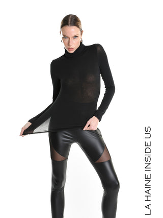 Das La Haine Pulli LW5232 black zeigt ein figurbetontes, leicht transparentes, schwarzes Rollkragenoberteil mit Kaschmiranteil, getragen von einem Model mit schwarzen Kunstlederleggings, vor einem weißen Hintergrund.