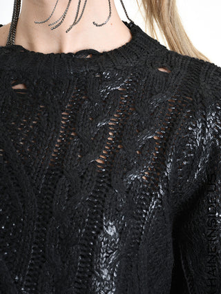 Nahaufnahme eines Oberkörpers im La Haine Sweater LW5136 black mit lockerem Zopfmuster und hohem, geripptem Kragen. Ein Kettenanhänger oder Ohrring schwebt über dem Kragen.