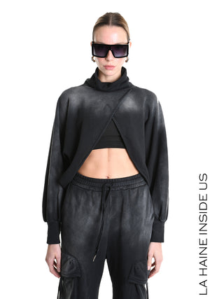 La Haine Sweater LW5226 black: Model trägt einen verkürzten, überkreuzten schwarzen Sweater mit weitem Stehkragen und langen Ärmeln, kombiniert mit schwarzen Jogger-Hosen und dunklen, übergroßen Sonnenbrillen.