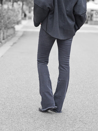 Eine Person trägt Gitta Banko Alba Flared Jeans W. Black mit ausgefranstem Saum, kombiniert mit einem weiten dunklen Oberteil. Schwarze Schuhe sind unter den ausgestellten Jeans sichtbar.