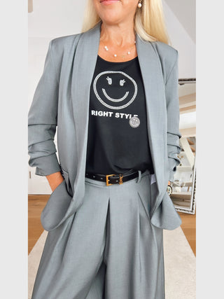 Person in grauem Anzug trägt das Doris Streich Shirt 268270 schwarz mit glitzerndem Smiley und RIGHT STYLE-Schriftzug, ergänzt durch einen schwarzen Gürtel mit goldener YSL-Schnalle.