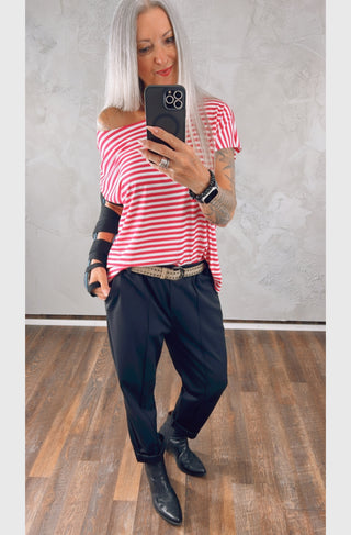 Person mit langen grauen Haaren trägt OFF#DLY Joggpant Riva black, kombiniert mit rotem Streifentop und schwarzen Stiefeletten, Spiegel-Selfie zeigt Komfort und Stil der modernen, italienisch inspirierten Hose.