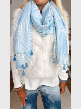 Torsoansicht mit OFF#DLY Schal Waves Fransen blau/beige, locker um den Hals gelegt; kombiniert mit einem weißen Faux-Fur-Westen und mittleren blauen Jeans. Accessoires sind goldene Armbänder.