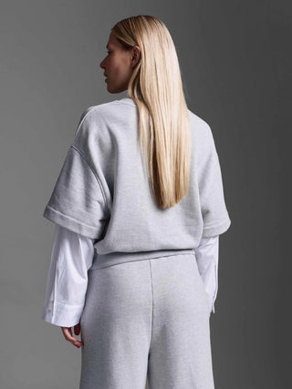 Person von hinten in Cotton Candy Sweatshirt Manel grey melange, hellgraues Sweatshirt mit kurzen Ärmeln über weißem Langarmshirt, passende graue Jogginghose, lässiger Oversized-Look, ideal für vielseitige Kombinationen.