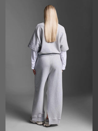 Person von hinten in Cotton Candy Pant Mako grey/melan: hellgraue, weite Sweathose mit kleinem Seitenschlitz am Saum, kombiniert mit passendem Sweatshirt und weißen Sneakern. Lässiges, athleisure Outfit.