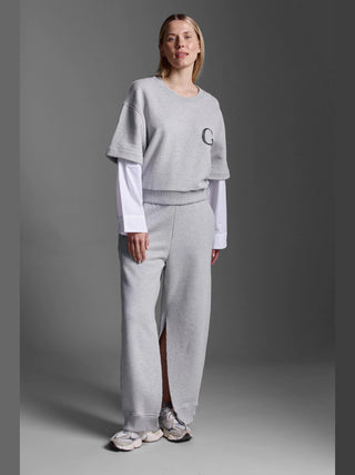 Person trägt Cotton Candy Pant Mako grey/melan, weite Sweathose mit elastischem Bund und offenen Seitennähten, kombiniert mit einem sportlichen, geschichteten Look aus kurzärmeligen Sweatshirt und langen Shirt.