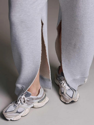 Nahaufnahme der Cotton Candy Pant Mako grey/melan mit offenen Seitennähten, getragen mit klobigen Sneakers. Die Sweatpants haben ein Oversized-Design und sind aus schwerem Baumwoll-Polyester-Mix gefertigt.