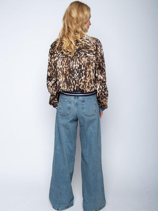 Person trägt Emily Bluse 8731-157512 Leo mit Leopardenmuster, blouson-artigem Schnitt und Hemdblusenkragen. Kombiniert mit hochtaillierten, weit geschnittenen blauen Jeans.