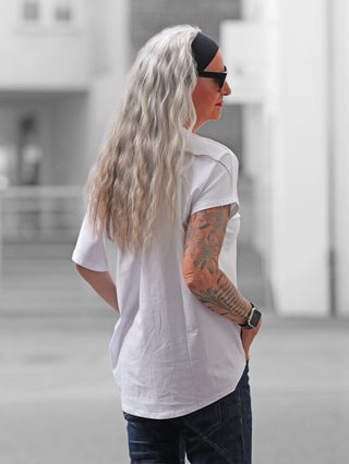 Eine Person trägt das OFF#DLY Tee LUCKY white, ein weißes T-Shirt mit auffälligem Frontprint von Leo-Würfeln, „777“ und „feeling lucky“, kombiniert mit dunklen Jeans.
