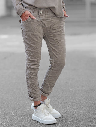 OFF#DLY Joggpant Bari grey – Leicht gekrempelte, hellgraue Hose mit Crinkle-Optik, getragen mit weißen Sneakern und schwarzem Perlenfußkettchen, präsentiert im entspannten Street-Style auf gepflastertem Boden.