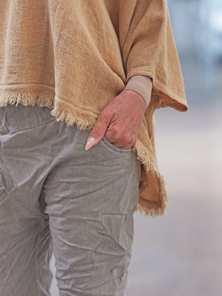 OFF#DLY Shirt Arianna camel: Locker sitzende, beige Tunika mit Fransen, aus Baumwoll-Leinen-Mix, betont durch lässigen, fließenden Schnitt. Perfekt für mediterrane Sommerlooks, kombiniert mit hellgrauen Hosen.