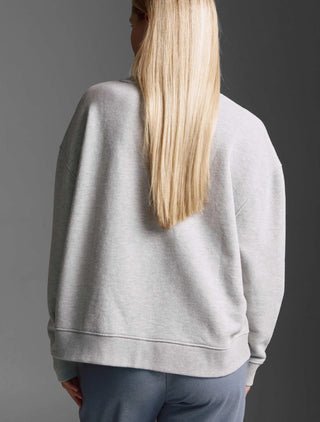Person von hinten mit langen, glatten, blonden Haaren trägt das oversized Cotton Candy Sweatshirt Manon grey melange mit Rundhals und offenen Seitennähten.