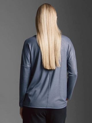 Person von hinten in einem locker sitzenden, gerippten Langarmshirt mit überschnittener Schulter und Rundhals. Das Cotton Candy Tee Margaux blue ash zeigt subtilen Glitterprint und ist oversized geschnitten.
