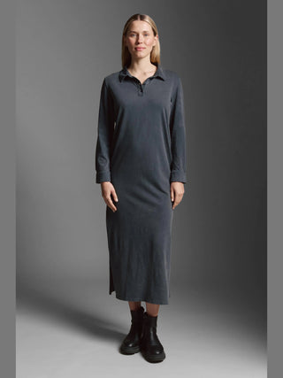 Frau trägt das Cotton Candy Dress Magnolia black, ein langärmeliges Polo-Maxikleid mit Seitenschlitzen, kombiniert mit klobigen schwarzen Stiefeletten.