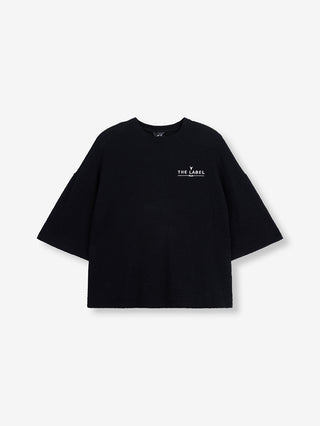 ALIX Boucle Tee black: Boxy geschnittenes, schwarzes T-Shirt aus Bouclé-Jersey mit kurzen Ärmeln, rundem Ausschnitt, und kleiner „THE LABEL / A|X“-Stickerei auf der linken Brust.