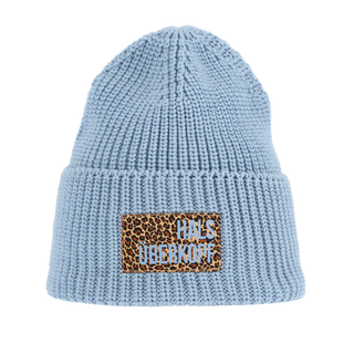 Die Halsüberkopf Mütze Leo Batch blau zeigt eine hellblaue, ribbgestrickte Beanie mit umgeschlagenem Saum und einem leopardengemusterten Patch mit der Aufschrift „HALS ÜBER KOPF“ auf dem Saum.