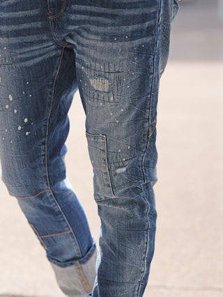 OFF#DLY Denim Livorno midblue Jeans mit auffälligem Patchwork-Look, sichtbaren Reparaturen, dezenten Used-Effekten und hochgekrempelten Säumen. Lässige Passform für urbanen Stil, ideal für vielseitige Outfits.
