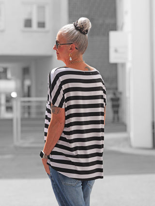 Ältere Frau im OFF#DLY Marion Stripe Tee, schwarz/weiß gestreift, locker sitzend, mit Rundhalsausschnitt und kurzen Ärmeln, kombiniert mit blauen Jeans, zeigt lässigen, stilvollen Look.