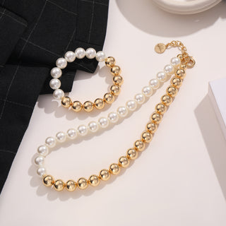 OFF#DLY Kugel/Perle Kette white/gold zeigt eine Halskette mit weißen Kunstperlen und goldenen Kugeln, ergänzt durch ein passendes Armband. Ein Stoff mit Fensterkaro-Muster und ein weißer Rand sind sichtbar.