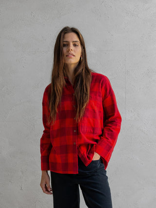 Frau trägt Penn&Ink Bluse tomato mit lockerem Schnitt, Knopfverschluss und Brusttasche, vor grauer Wand. Die Bluse hat einen klassischen Kragen, perfekt für lässig-elegante Looks.