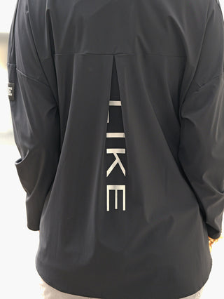 Doris Streich Tunika 401600 schwarz: Rückansicht einer leichten Jacke mit mittigem Rückfalten-Detail, durch das HIKE sichtbar ist; sportliches Design, lange Ärmel, ein Ärmel mit kleinem Patch.