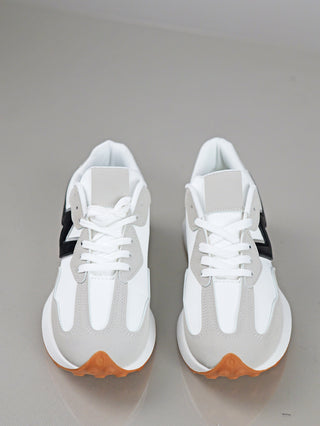 OFF#DLY Sneaker white mit weißen Oberflächen, hellgrauen Wildleder-Overlays und schwarzem Akzentpanel, auf gum-braunen Gummisohlen, präsentiert auf einer glatten, hellgrauen Fläche.