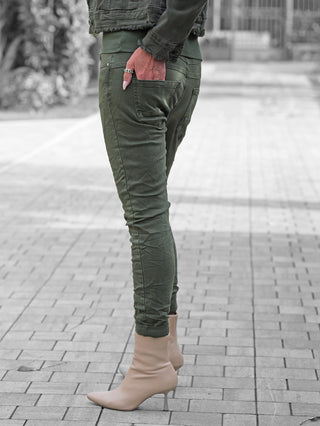 OFF#DLY Color Jeans Imelda khaki in schlanker Passform, getragen mit beigen Stiefeletten. Die Hose betont die Figur und bietet Komfort durch leichtes Stretchmaterial. Slim-Fit-Design mit modernem Knopfverschluss.