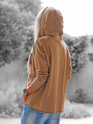 Eine Person trägt den OFF#DLY Shirt Be Happy camel Hoodie mit Kapuze, kombiniert mit hellblauen Jeans. Der Hoodie zeigt einen coolen Frontprint und vermittelt lässige, positive Vibes.