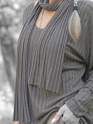 Nahaufnahme des OFF#DLY Longsleeve Sigrid schoko mit Rippenstrick und passendem Schal. Die elegante Struktur wird durch ein silbernes Halsketten-Detail und einen Ring ergänzt.