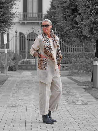 Ältere Frau trägt OFF#DLY Weste Alva stone mit Leo-Details an Kragen und Taschen, kombiniert mit einem lässigen Outfit, das die Vielseitigkeit und den stilvollen Look der Weste unterstreicht.