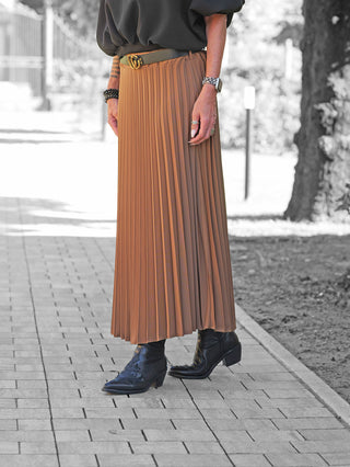 OFF#DLY Plissee Rock camel: Ein caramel-brauner, knöchellanger Plisseerock mit schwarzem Ledergürtel und goldener Double-G-Schnalle, kombiniert mit schwarzen Lederstiefeletten und Schmuck an den Händen.