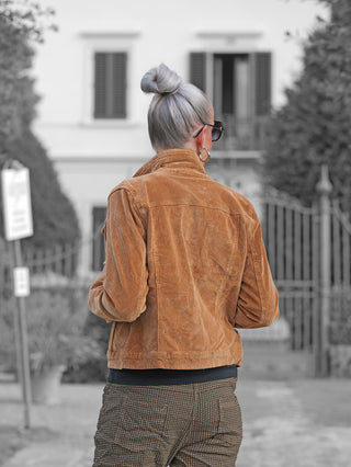 Eine Person trägt die OFF#DLY Jacke Elettra Zimt, eine warme Cordjacke mit klassischem Design und Knopfleiste, ergänzt durch große Hoop-Ohrringe und eine dunkle Sonnenbrille.