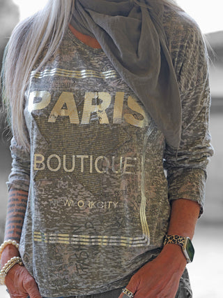 Das OFF#DLY Shirt Paris taupe zeigt einen urbanen Look mit metallisch-goldenem Paris-Print. Kombiniert mit einem leichten Schal, Leopard-Uhrband und Schmuck, wirkt es modisch und vielseitig.