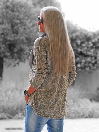 Person trägt das OFF#DLY Shirt Paris taupe, ein langärmeliges, gemustertes Oberteil in gedämpften Tönen, kombiniert mit leicht ausgewaschenen Jeans und einer Smartwatch, vor unscharfem, schwarz-weißem Hintergrund.