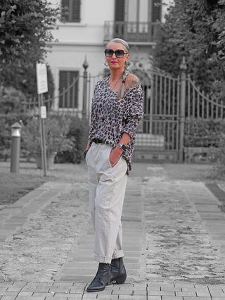 Die OFF#DLY Longsleeve Astrid beige/black zeigt eine Frau im lässigen, schulterfreien Leopardenmuster-Oberteil, ideal für modische Akzente. Perfekt kombiniert mit hellen Hosen und Accessoires.