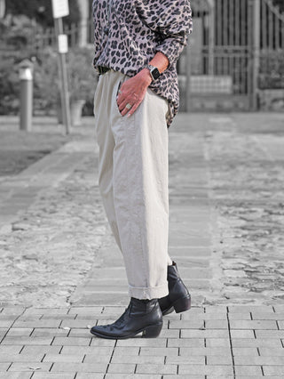 OFF#DLY Pant Melania stone: Locker geschnittene, hellbeige Hose mit hoher Taille und Umschlag am Knöchel, getragen mit schwarzen Lederstiefeletten und einer Smartwatch mit animalischem Armband.