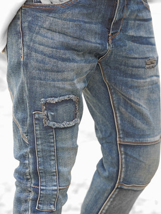Nahaufnahme einer Person mit OFF#DLY Denim Ilaria darkblue Jeans. Die Jeans zeigt markante Destroy-Details, Abnäher und ein verwaschenes Finish mit fransigem Patch und verstärkten Nähten.