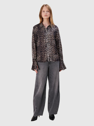 Das Model trägt die True Religion Ruby Volume Jeans: weite, hochtaillierte, ausgewaschene Jeans mit offenem Saum. Kombiniert mit einer Leopardenbluse und schwarzen Leder-Mules.