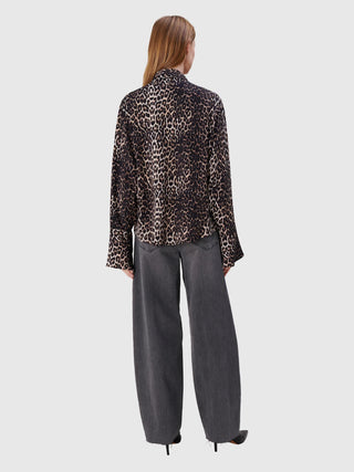 Frau von hinten in True Religion Ruby Volume: locker geschnittene Bluse mit Leopardenmuster, hochgeschnittene, weit geschnittene Jeans mit offenem Saum und schwarze spitze High Heels.