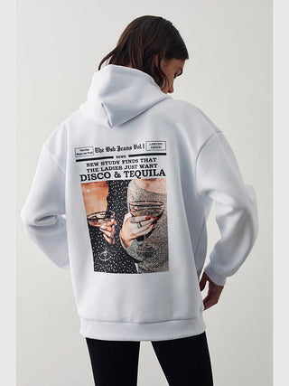 Person trägt BSB Bluse 210084 white, einen übergroßen weißen Hoodie mit Zeitungsstil-Grafik auf dem Rücken, die die Schlagzeile NEW STUDY FINDS THAT THE LADIES JUST WANT DISCO & TEQUILA zeigt.