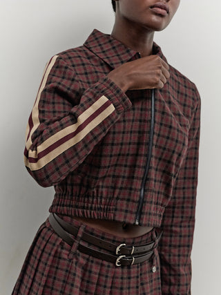 BSB Jacke 217014 burgundy: Kurze, karierte Jacke mit Reißverschluss und beige-maroon Streifen an den Ärmeln, kombiniert mit einem passenden plissierten Rock und einem doppelschnalligen Lederbund in Dunkelbraun.