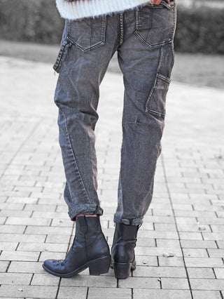 Die OFF#DLY Denim Beatrice black washed Jeans in grau, mit markanter Waschung und aufgesetzten Taschen, wird lässig mit schwarzen Lederstiefeletten und einem weißen, flauschigen Pullover kombiniert.