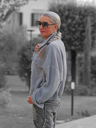 Eine Frau trägt die OFF#DLY Jacke Zaira grey, eine graue, kurz geschnittene Jacke mit Hemdkragen und aufgesetzten Taschen, perfekt für einen lässigen, stilvollen Look.