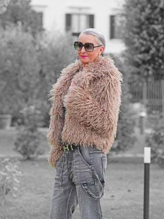 Ältere Frau draußen in einer OFF#DLY Fake Fur Jacke beige, mit voluminöser Fake-Fur-Optik, kombiniert mit grauen Cargo-Jeans. Die Jacke bietet stilvolle Wärme und Komfort für kalte Tage.